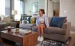 woman sits on her couch in sun-filled living room