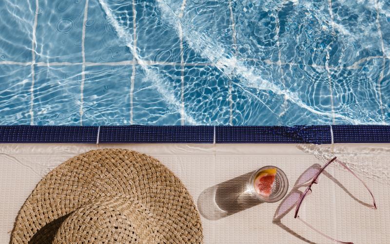 a hat and sunglasses near a pool's edge